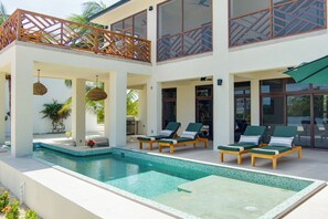 Ein Poolbereich mit Liegestühlen, einer Pergola und Blick auf das Meer.