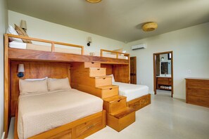 Ein Zimmer mit zwei Etagenbetten, einer Holzkommode und einem Spiegel.