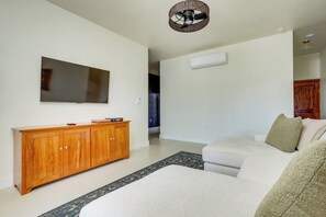 Ein modernes Wohnzimmer mit Flachbildfernseher, Holzschrank und einer Couch.