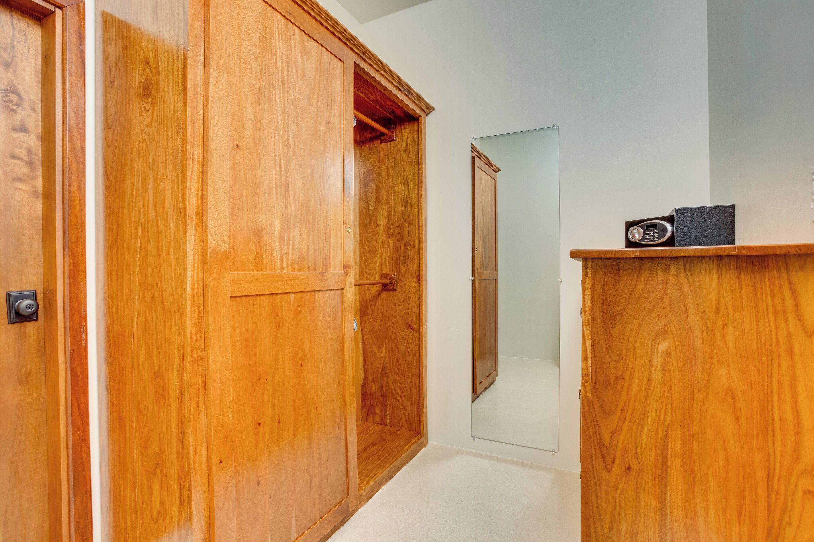 A wooden wardrobe with a mirror, a small shelf with a radio, and a door leading to a bathroom.