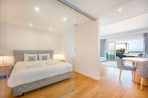 Une chambre d’hôtel moderne avec un grand lit, un bureau et une vue sur la mer.