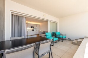 Une chambre d’hôtel compacte dotée d’une kitchenette, d’un coin repas avec une table et des chaises, et d’un balcon aménagé avec des sièges.