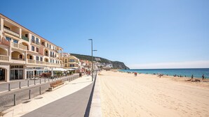 Une rue côtière bordée d’immeubles, avec un trottoir et une plage.