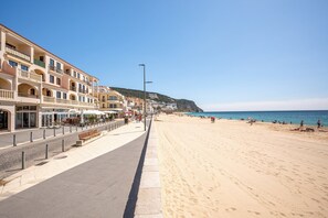 Eine Küstenstraße mit Gebäuden, einem Bürgersteig und einem Strand.