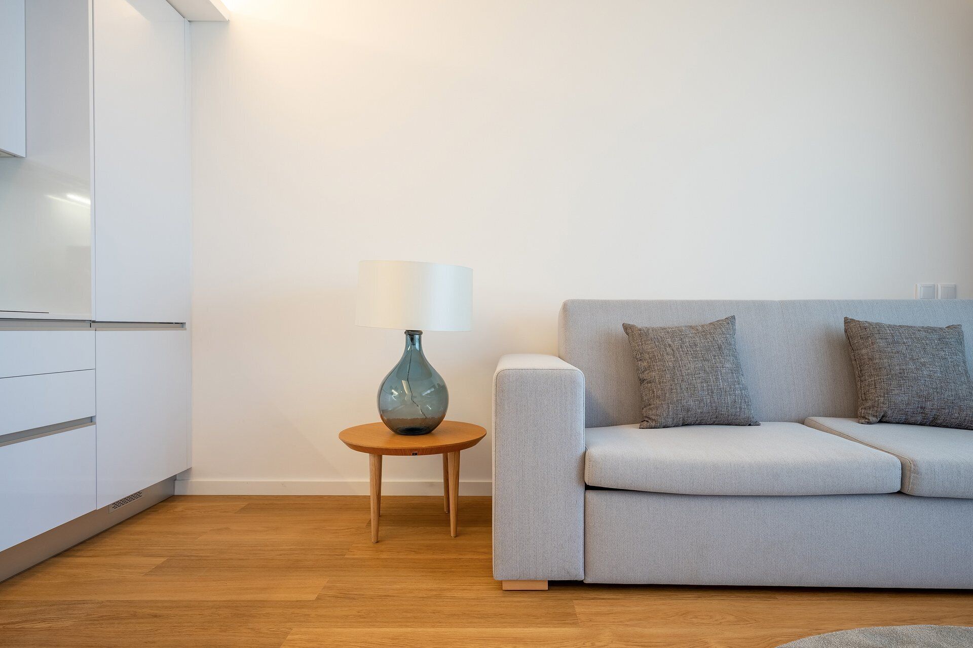 Una sala de estar moderna con un sofá, una lámpara y una pequeña mesa auxiliar de madera.