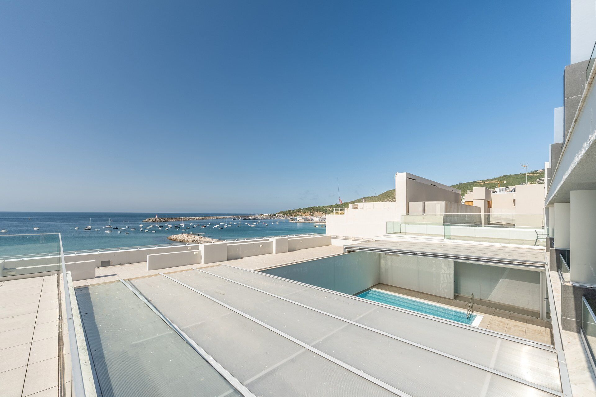 A rooftop pool with a clear view of the sea and boats.