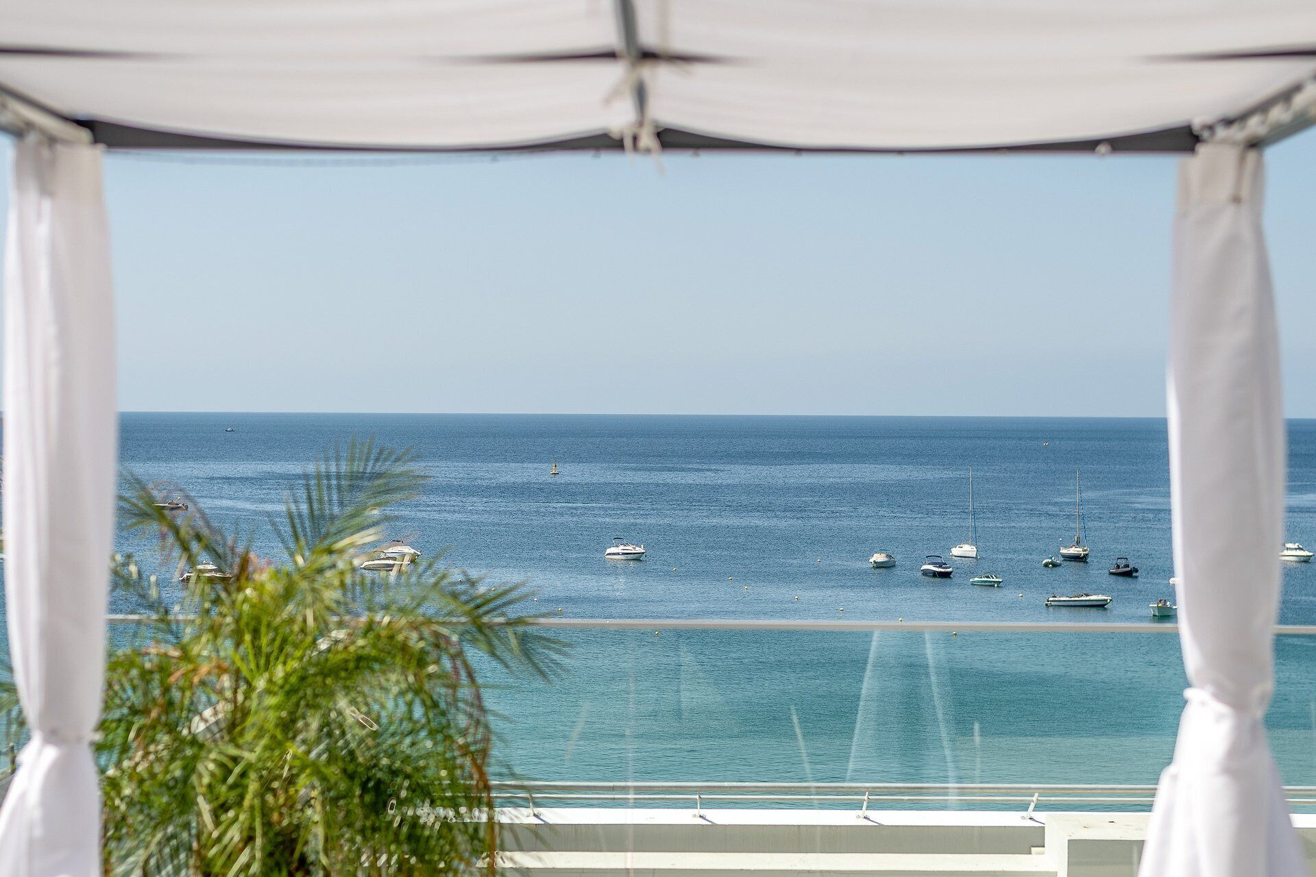 A view of the sea from a balcony with a white canopy overhead.