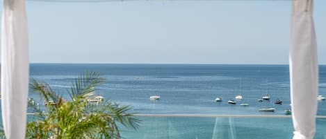 A view of the sea from a balcony with a white canopy overhead.