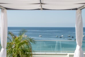 Une vue sur la mer depuis un balcon surmonté d’un auvent blanc.