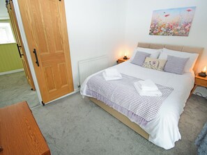 A bedroom with a bed, bedside lamps, a radiator, a wooden door, and a painting on the wall. - 1 bedroom accommodation in Cockermouth (Cockermouth)