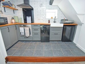 A compact kitchen with grey cabinets, a dishwasher, and a microwave. - 1 bedroom accommodation in Cockermouth (Cockermouth)