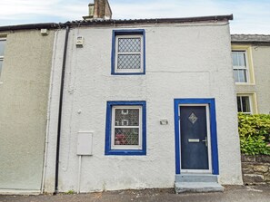 A two-story building with a blue-framed door and windows, a small step leading to the entrance, and a sign indicating a 'Cottage College.' - 1 bedroom accommodation in Cockermouth (Cockermouth)