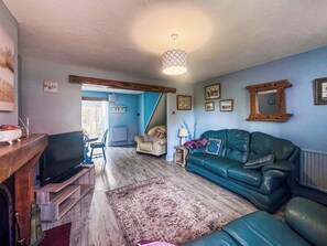 Ein Wohnzimmer mit Fernseher, Sofa und einem gemusterten Teppich.