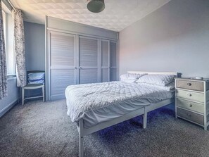 Ein Schlafzimmer mit einem Bett, einem Nachttisch, einem Sessel und einem Kleiderschrank.