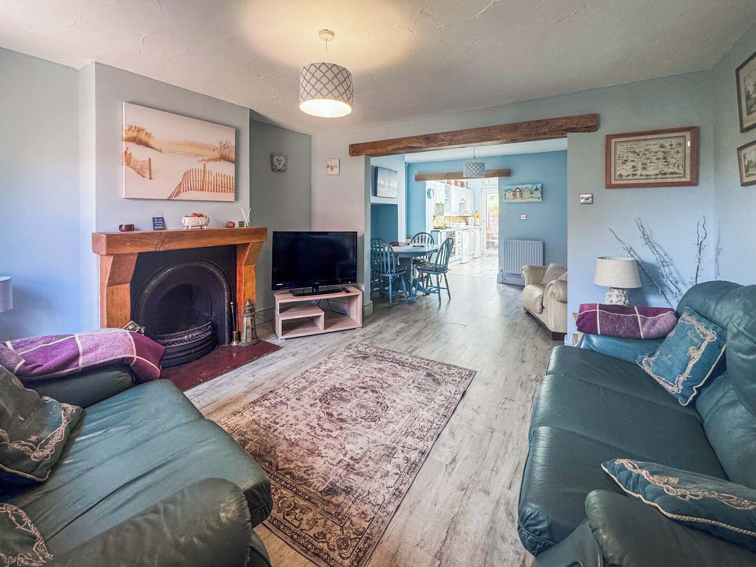 A living room with a fireplace, television, sofa, and a dining area with chairs and a table.