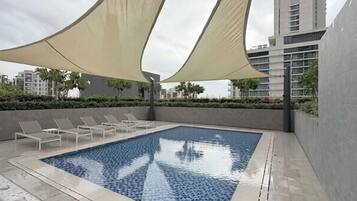 Une piscine dotée de chaises longues et surmontée d’un grand auvent.