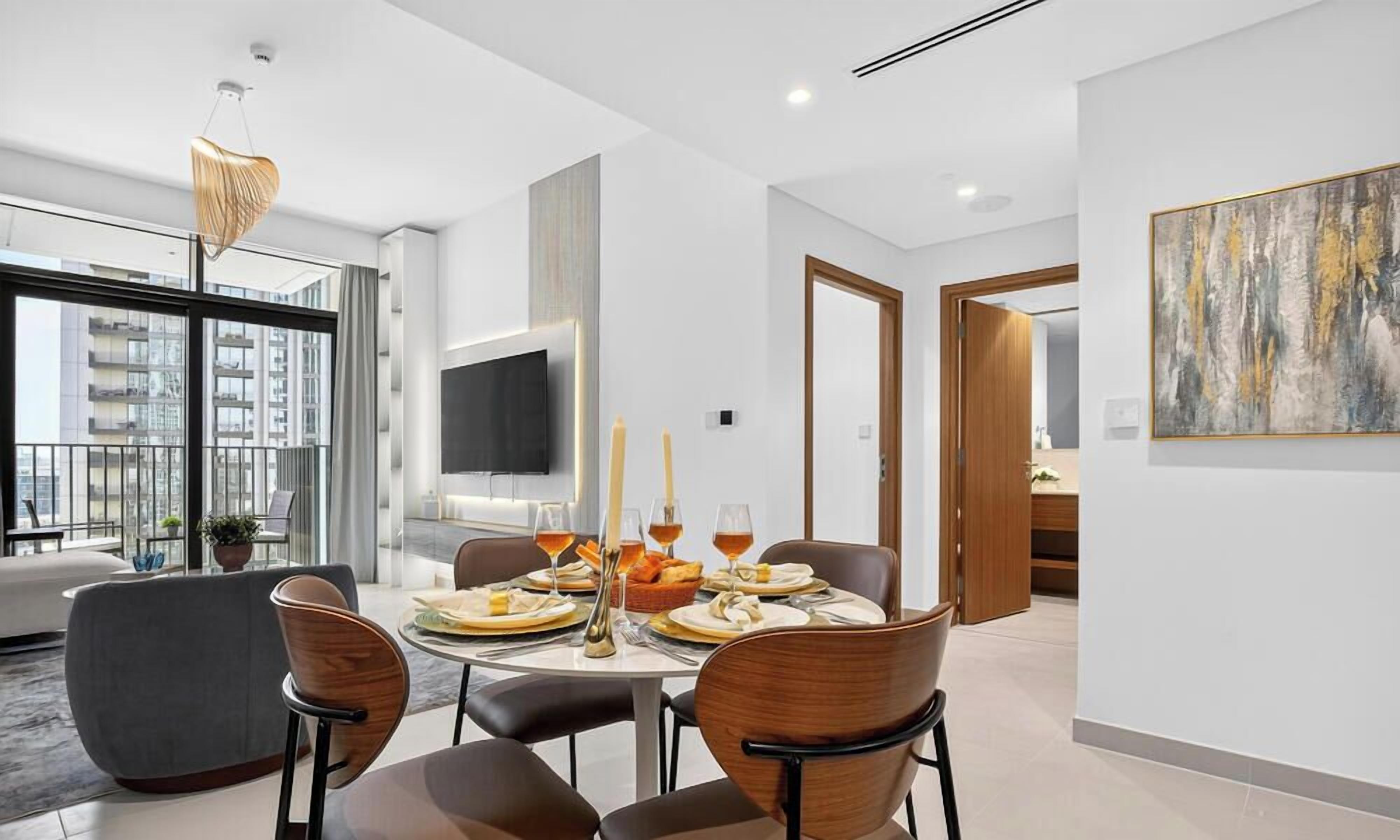 Un espace repas moderne avec une table ronde, des chaises et un téléviseur fixé au mur.