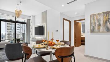 Un espace repas moderne avec une table ronde, des chaises et un téléviseur fixé au mur.