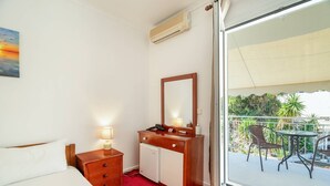 A hotel room with a bed, bedside table, dresser, mirror, and a balcony with outdoor furniture. - Room '1st Floor' with Sea View, Shared Pool and Wi-Fi (Nikiana)