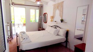 A bedroom with a bed, a bedside table, a mirror, and a window. - Room '1st Floor' with Sea View, Shared Pool and Wi-Fi (Nikiana)