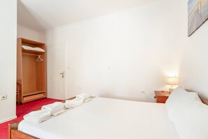 A bedroom with a bed, a wardrobe, a bedside table with a lamp, and a painting on the wall. - Room '1st Floor' with Sea View, Shared Pool and Wi-Fi (Nikiana)