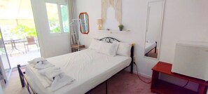 Een kamer met een bed, een stoel, een tafeltje, een spiegel en een raam.