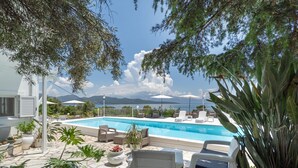 Ein Poolbereich mit Liegestühlen, Topfpflanzen und Blick auf Berge.