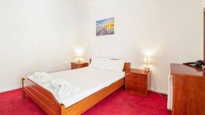 Ein Hotelzimmer mit einem hölzernen Bett, zwei Nachttischen mit Lampen, einem roten Teppich und einem Gemälde an der Wand.