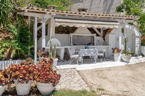 A patio with a grill, white chairs, and potted plants. - 'First Floor' Room Shared Pool and Wi-Fi (Nikiana)