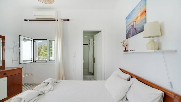 A hotel room with a bed, a desk, a window with a view, and a painting on the wall. - Room 'Ground Floor' Shared Pool and Wi-Fi (Nikiana)
