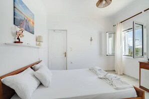 Une chambre à coucher avec un lit, une porte, une fenêtre et un tableau accroché au mur.