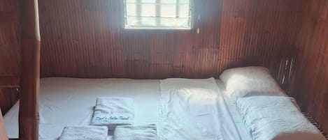 Una cama individual con ropa de cama blanca y dosel, una ventana con persianas y una puerta con pomo redondo.
