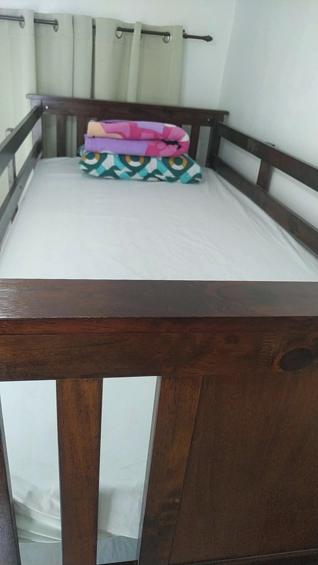 A single bed with a wooden headboard and a mattress.