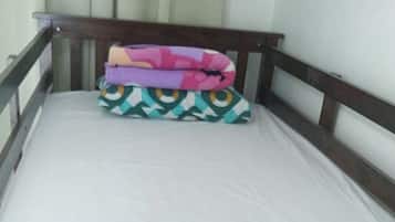 A single bed with a wooden headboard and a mattress.