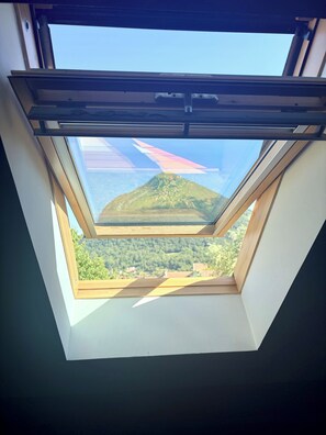A skylight with a view of a green landscape and a distant building. - Villa Mont Baret (Menthon-Saint-Bernard)