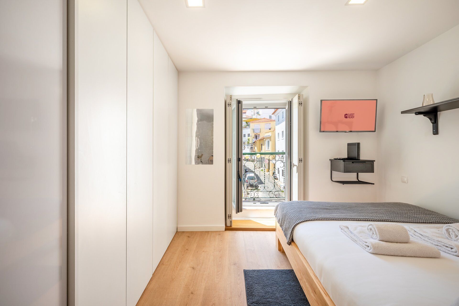 Habitació d'hotel amb un llit, un escriptori, un ordinador, una televisió i vista al carrer.