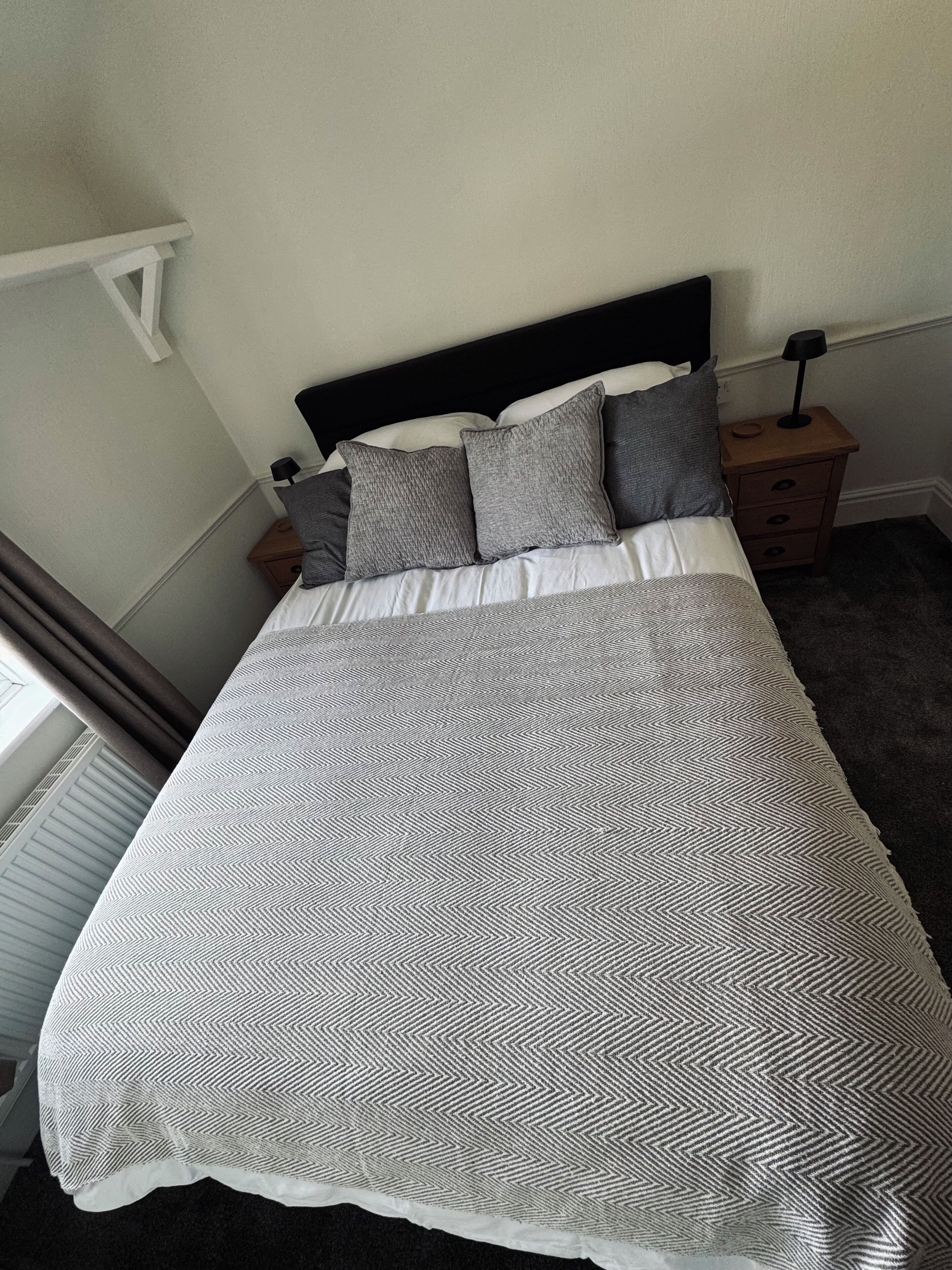 A bed with a patterned bedspread, a headboard, and a nightstand with a lamp.