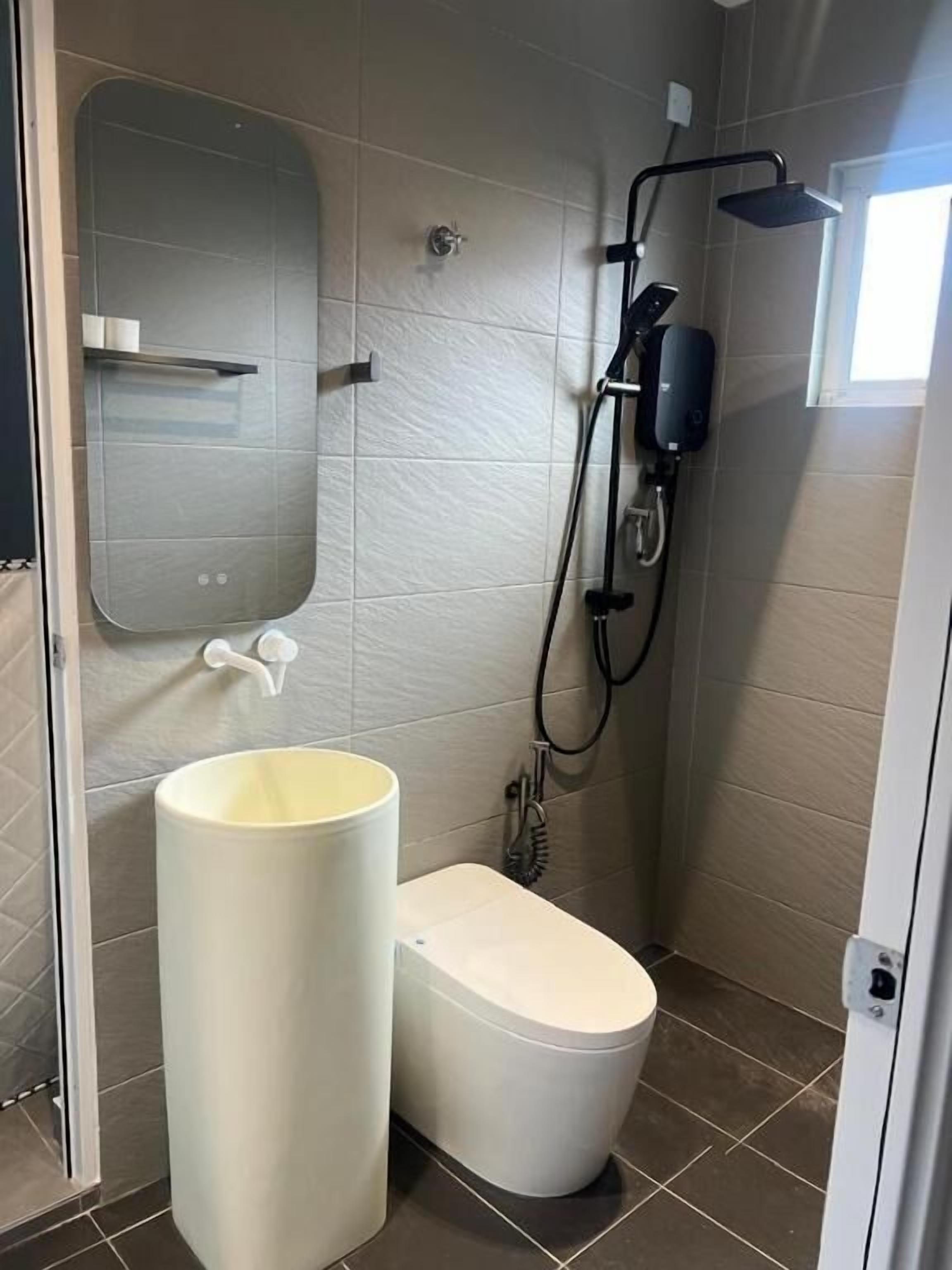 Un baño con inodoro, lavamanos, ducha y espejo.