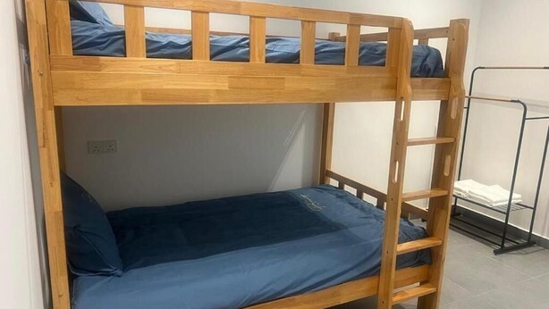 A bunk bed with a ladder, a metal rack, and a white towel rack.