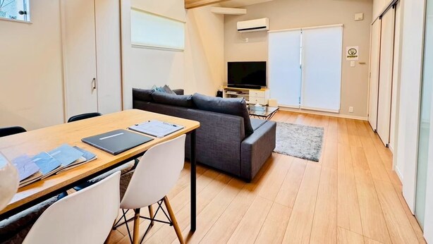 A modern living room with a sofa, a dining table with chairs, a television, and a large window. - 10 minutes from Okayama Station | Exclusive use for one group | Groups welcome | Up to 6 guests | 1 parking space | Loft | 1 restroom | Long-term stays welcome (岡山市)