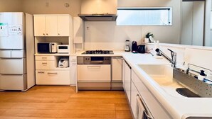 A modern kitchen with white cabinetry, a built-in microwave, a gas stove, and a stainless steel sink. - 10 minutes from Okayama Station | Exclusive use for one group | Groups welcome | Up to 6 guests | 1 parking space | Loft | 1 restroom | Long-term stays welcome (岡山市)