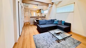 A modern living room with a sectional sofa, a glass coffee table, and a grey rug. - 10 minutes from Okayama Station | Exclusive use for one group | Groups welcome | Up to 6 guests | 1 parking space | Loft | 1 restroom | Long-term stays welcome (岡山市)