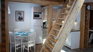 A compact kitchen with a microwave, refrigerator, and a wooden staircase. - Onnela 1 Chalet | Sauna & Ski Trails | Ruka (Kuusamo)