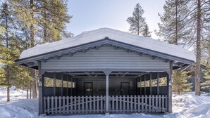 A covered pavilion with a white picket fence, surrounded by snow and trees. - Onnela 1 Chalet | Sauna & Ski Trails | Ruka (Kuusamo)