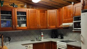 Una cucina con mobili in legno, un piano di lavoro, un lavello, un fornello e un frigorifero.