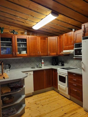 Une cuisine avec des meubles de rangement en bois, un plan de travail, un évier, une cuisinière et un réfrigérateur.