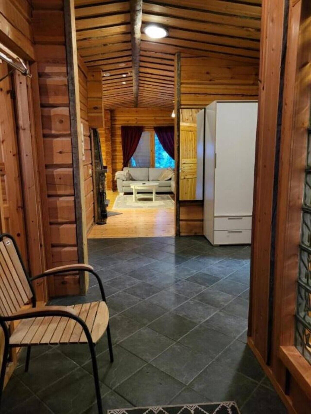 Un interior de madera con un sofá, una mesa de centro y un refrigerador.