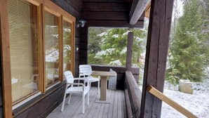 Un terrazza in legno con tavolo e sedie, affacciata su un paesaggio innevato.