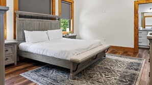 Ett sovrum med en säng, sängbord, en träpanel vid sänggaveln, ett fönster och en spegel.