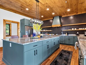A modern kitchen with a large island, wooden ceiling, and a honeycomb backsplash. - Sleeps 40 + 2 Indoor Pools + Game Rooms | The Spurling Collection (Sevierville)
